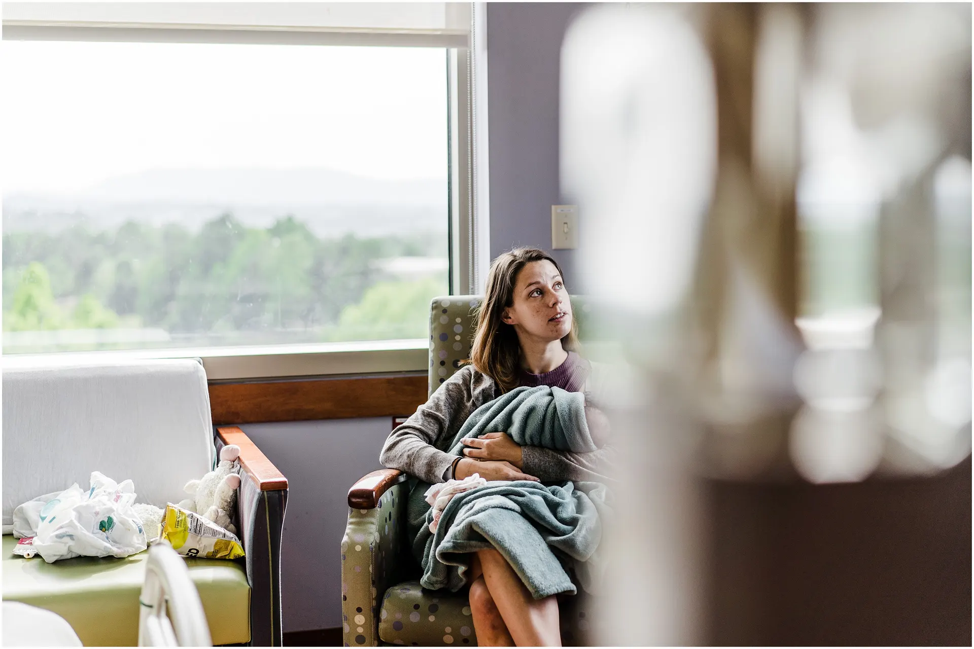 mother gazing calmly around the hospital with newborn baby