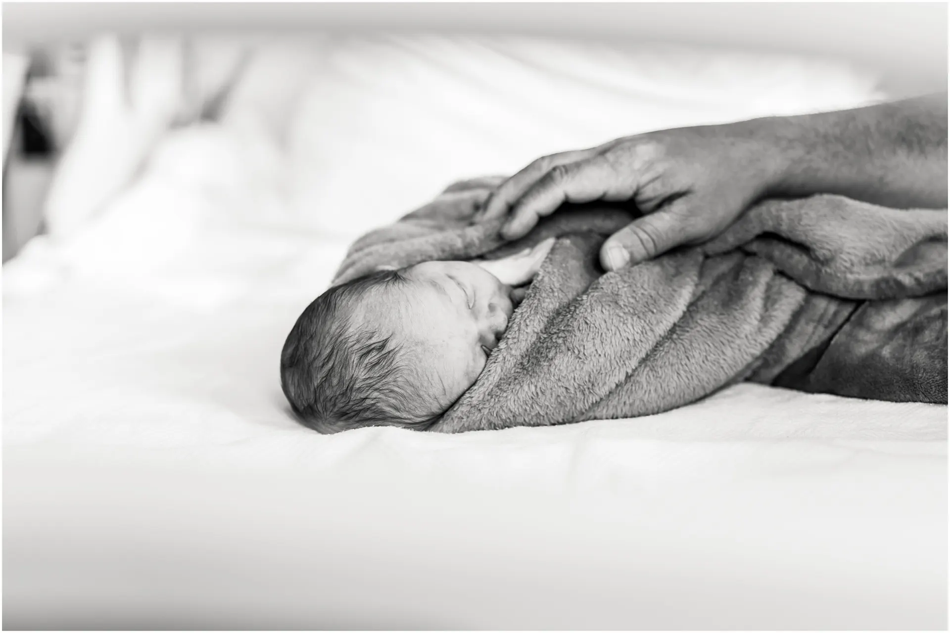 newborn baby girl wrapped in blankets laying on hospital bed