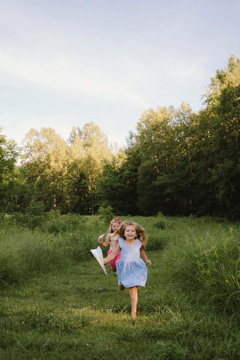 playful mini sessions in the summer, sisters running in a field