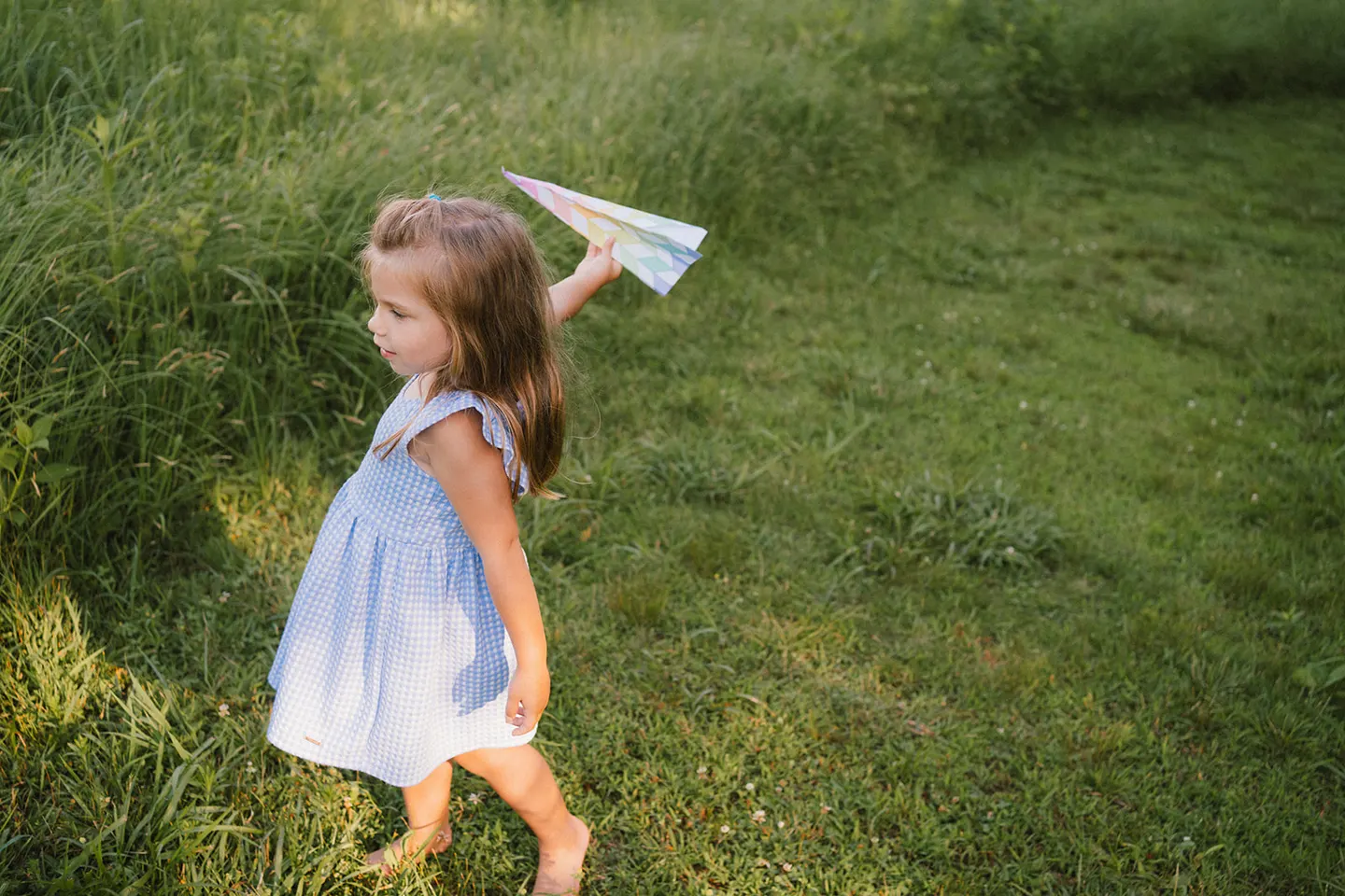 girl playing with paper airplane during family photos